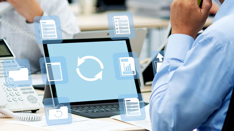 Close-up auf telefonierenden Mann am Computerarbeitsplatz mit darüber gelegten halbtransparenten Grafikelementen, die die digitale Bearbeitung von Anträgen symbolisieren
