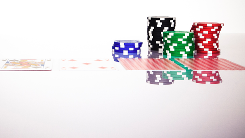 Pokerkarten und Casino-Chips auf einem Glastisch