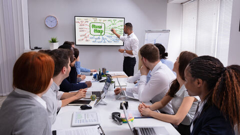 Im Seminarangebot der HZD und ihrer IT-Fortbildung: produktive Arbeitsmethoden Team im Besprechungsraum mit Tafel, auf der eine Mindmap zu sehen ist