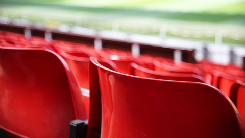 Userfreundlich und zielgerichtet – die Spielstättendatenbank der HZD Blick über rote Stuhlreihen auf das Spielfeld eines Fußballstadiums