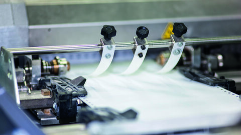 Nahaufnahme einer Druckmaschine, in der Papier durchläuft