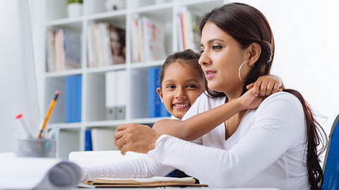 Ausgezeichneter Arbeitgeber: die HZD, die ihren Mitarbeitenden eine ganze Reihe attraktiver Benefits bietet Junge Frau am Schreibtisch im Homeoffice mit Tochter im Grundschulalter