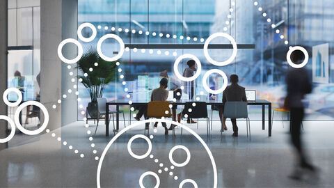 Gruppe von Menschen am Besprechungstisch mit darübergelegter Grafik aus Kreisen und Punkten, die ganzheitliches Projektmanagement symbolisiert