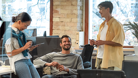 Blick in zeitgemäßes Büro mit drei jungen Menschen im Arbeitsgespräch