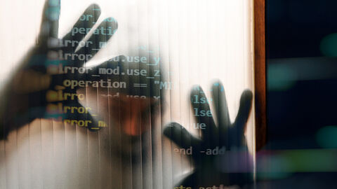 Effiziente Cyberabwehr – eine der Aufgaben des HZD-Informationssicherheitsmanagements Blick durch die gerippte Glasscheibe einer Tür, auf die ein schemenhaft erkennbarer Mann beide Hände gelegt hat, darüber gelegt eine Grafik aus Programmierbefehlen