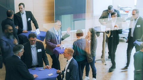Blick in einen Konferenzraum der HZD, in dem die Teilnehmerinnen und Teilnehmer des Kundenforums zum Programm Cloud-Transformation sich an Stehtischen angeregt austauschen 