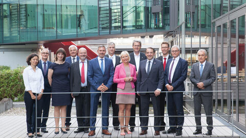 Mehrere Männer und drei Frauen lachen in Kamera