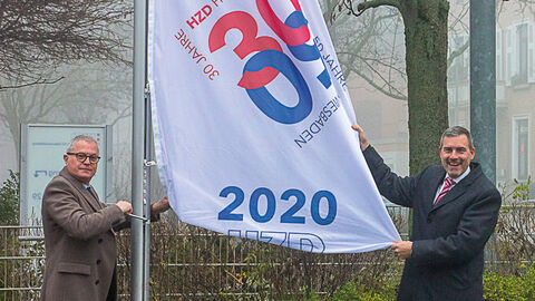 Jubiläumsflaggen 50-30 Zwei Männer hissen Flaggen