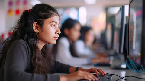 Einladung in die Welt der IT: der Girls' Day 2025 bei der HZD Close-up auf junges Mädchen, das neben anderen Mädchen in einer Schulklasse sitzt und aufmerksam auf einen Monitor sieht